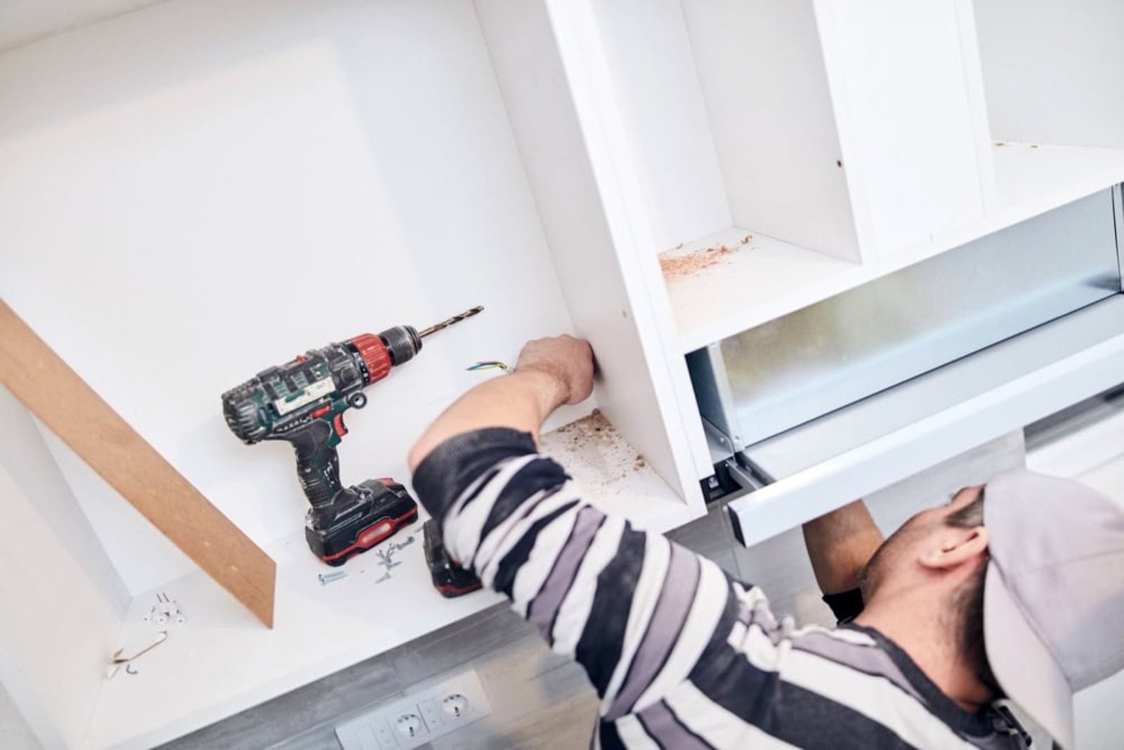 Handyman using a cordless drill to install a cabinet
