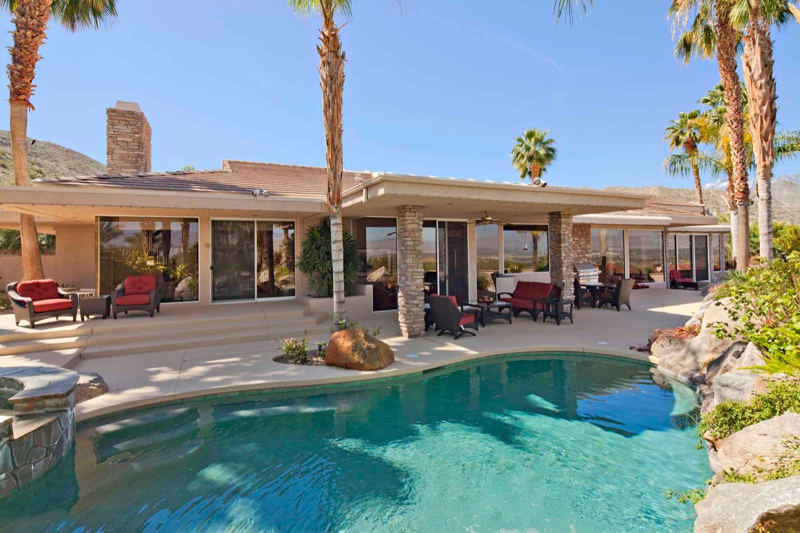 Backyard pool and covered patio at a desert home with mountains behind